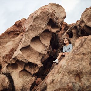 A child smiles from between some unique rocks found on the coast of the south western australia road trip to show the unique natural beauty found here